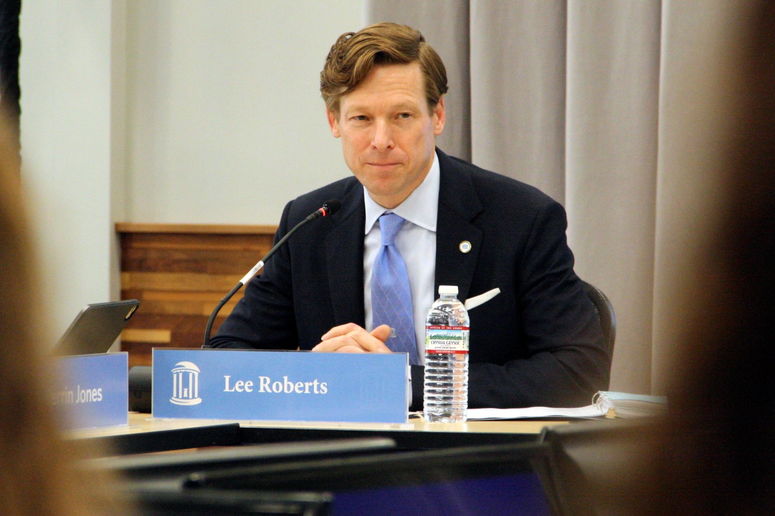 Lee Roberts sitting behind a sign that says his name